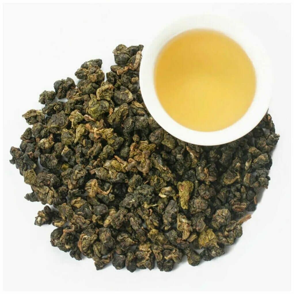 Сухие листья улуна и чашка чая на светлом фоне