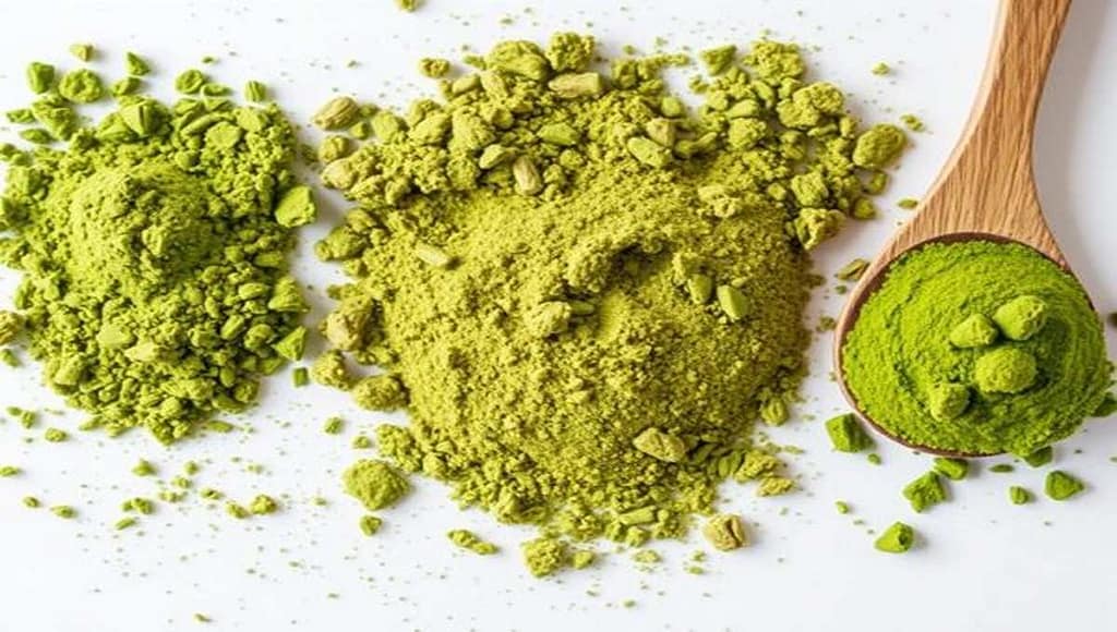 Порошок чая матча: три насыпи ярко-зелёного цвета и деревянная ложка на белом фоне