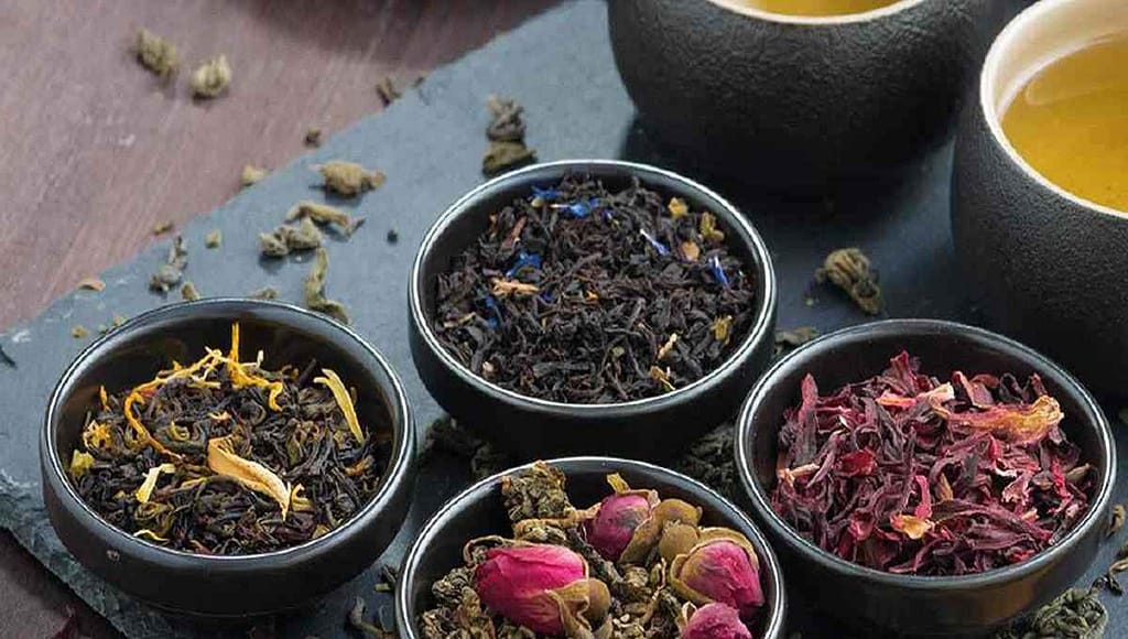 Ароматизированный чай: какие добавки выбрать и чем они полезны. Как выбрать ароматизированный чай в пакетиках? Ароматизированный чай: четыре вида листового — чёрный, зелёный с лепестками роз, гибискус и травяной с жёлтыми цветками на тёмном фоне