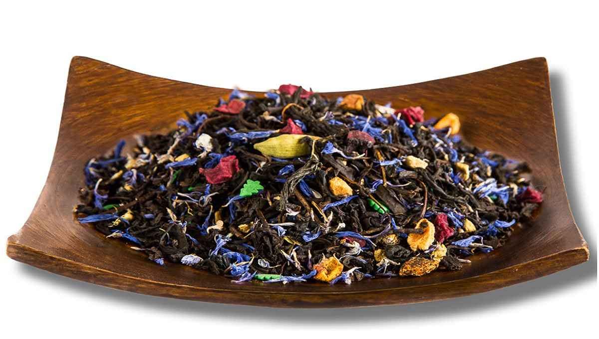 Цветочный листовой чай с цитрусовыми и лепестками в деревянной чаше Ассорти листового чая с лепестками василька, розы и кусочками сухофруктов в деревянной пиале