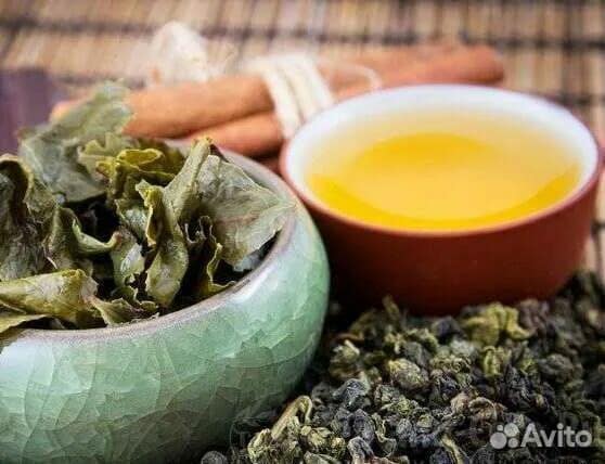 Красный чай в чашке, сушёные листья и корица на светлой поверхности